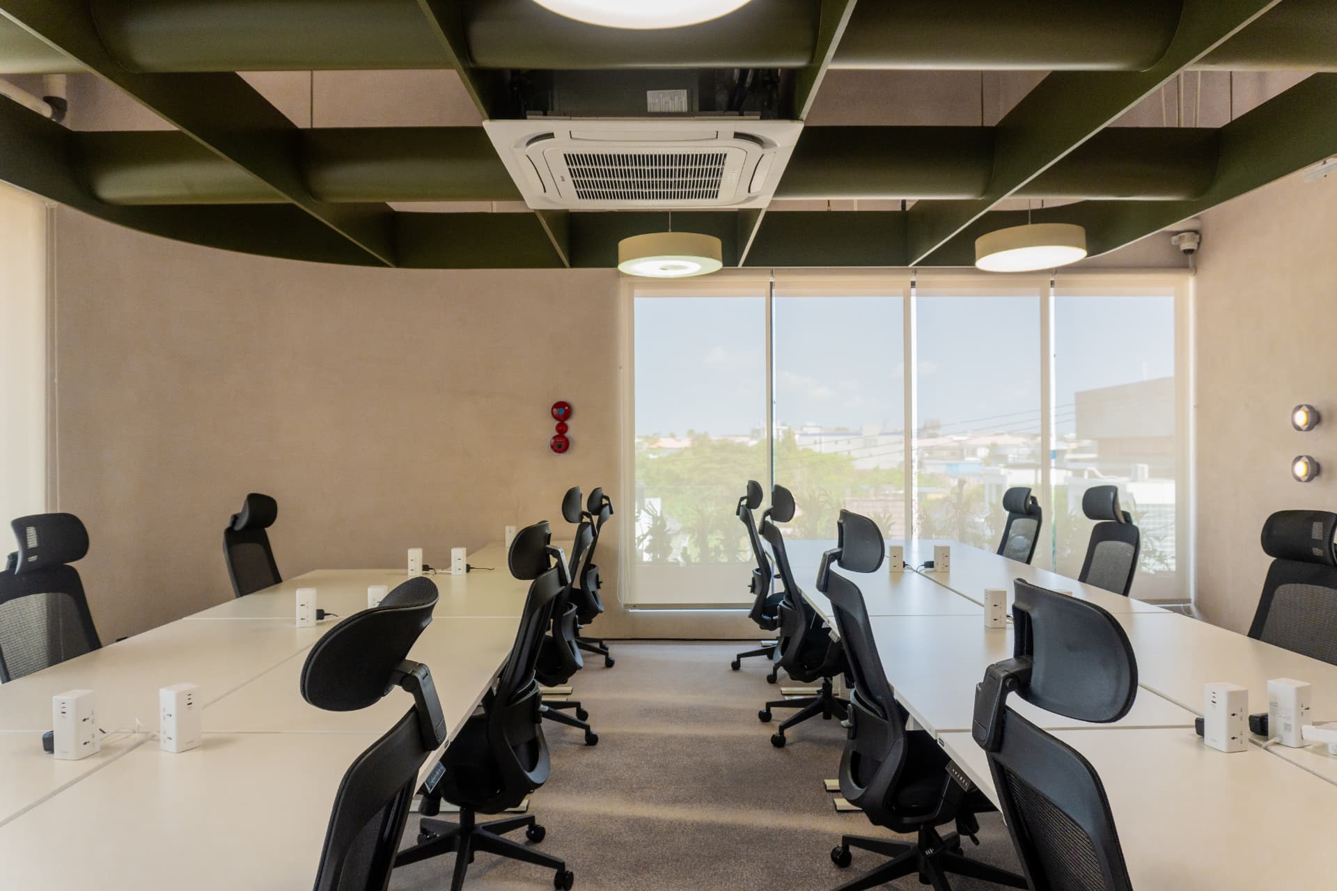 The open hot-desk floor at Argil in Pererenan, with desks and ergonomic chairs beside tall windows